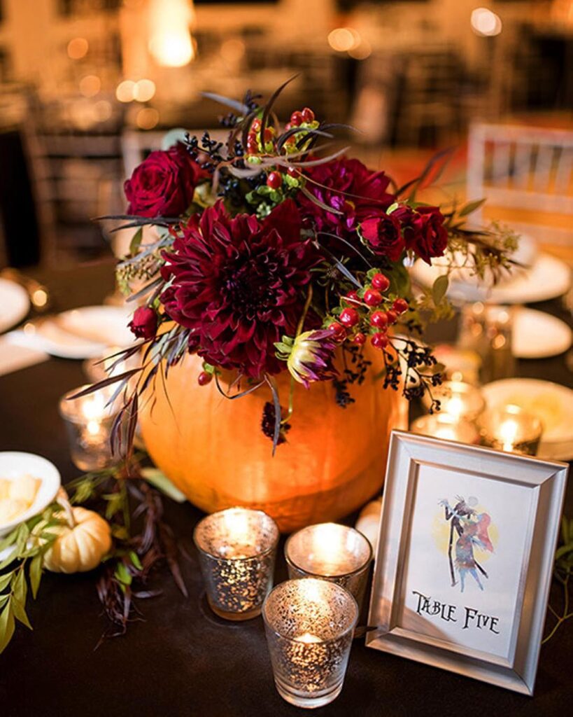 Elegant pumpkin wedding centerpiece with deep red flowers and candles for Table Five.