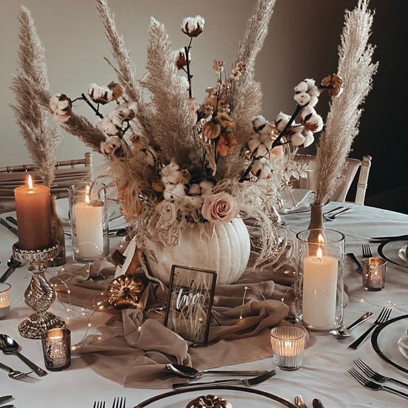 Elegant fall wedding centerpiece with pampas grass, cotton, and roses in a white pumpkin.