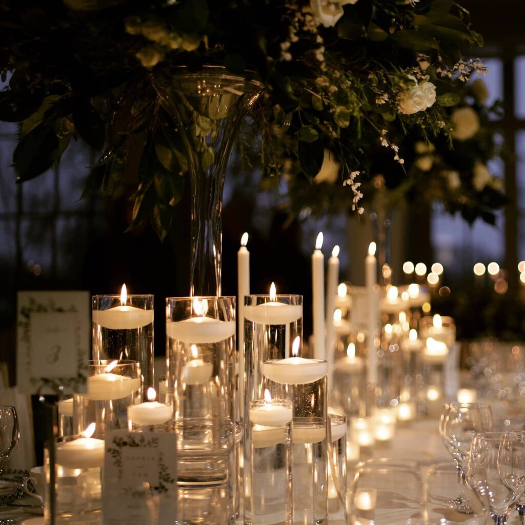 Elegant wedding reception table with floating candles and floral centerpieces.
