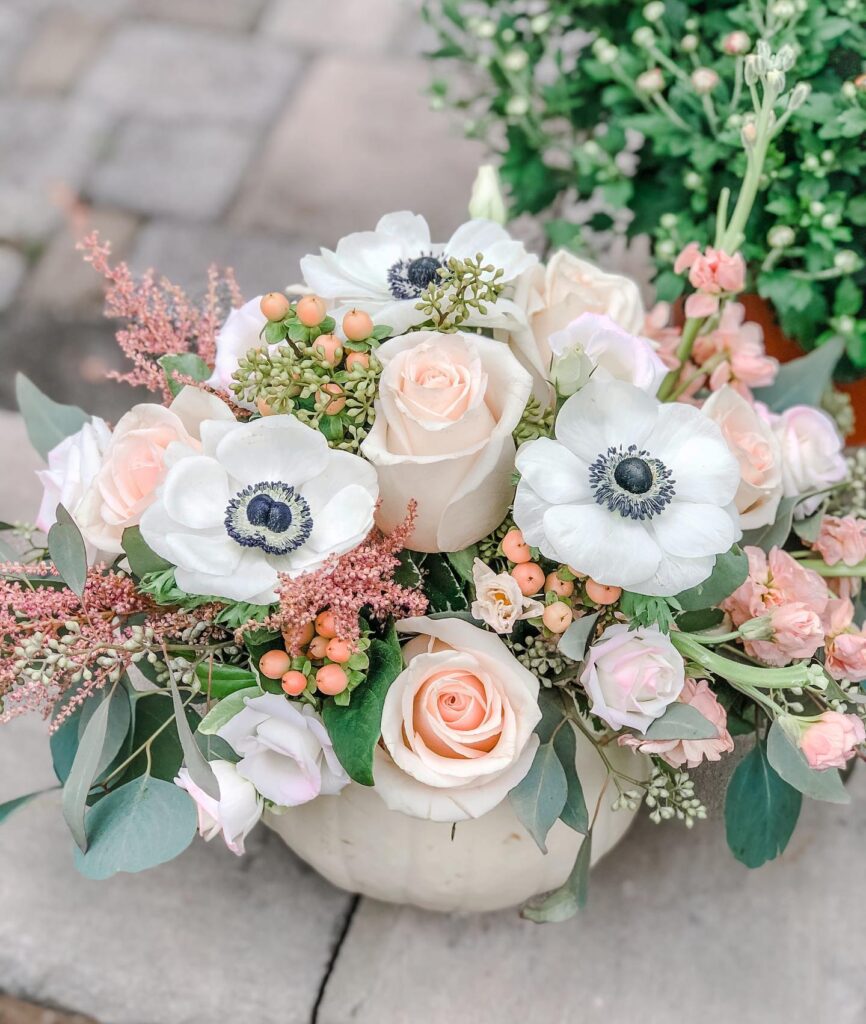 Elegant wedding centerpiece with white anemones, blush roses, and greenery.