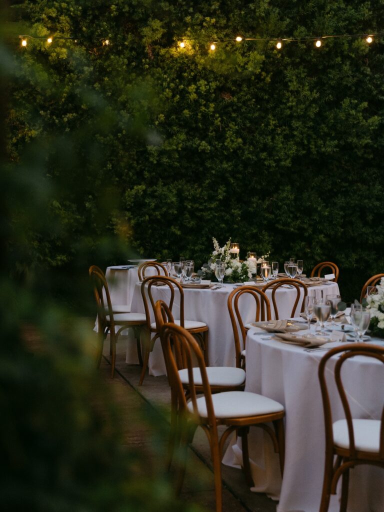 Elegant outdoor wedding reception with floating candles and string lights.