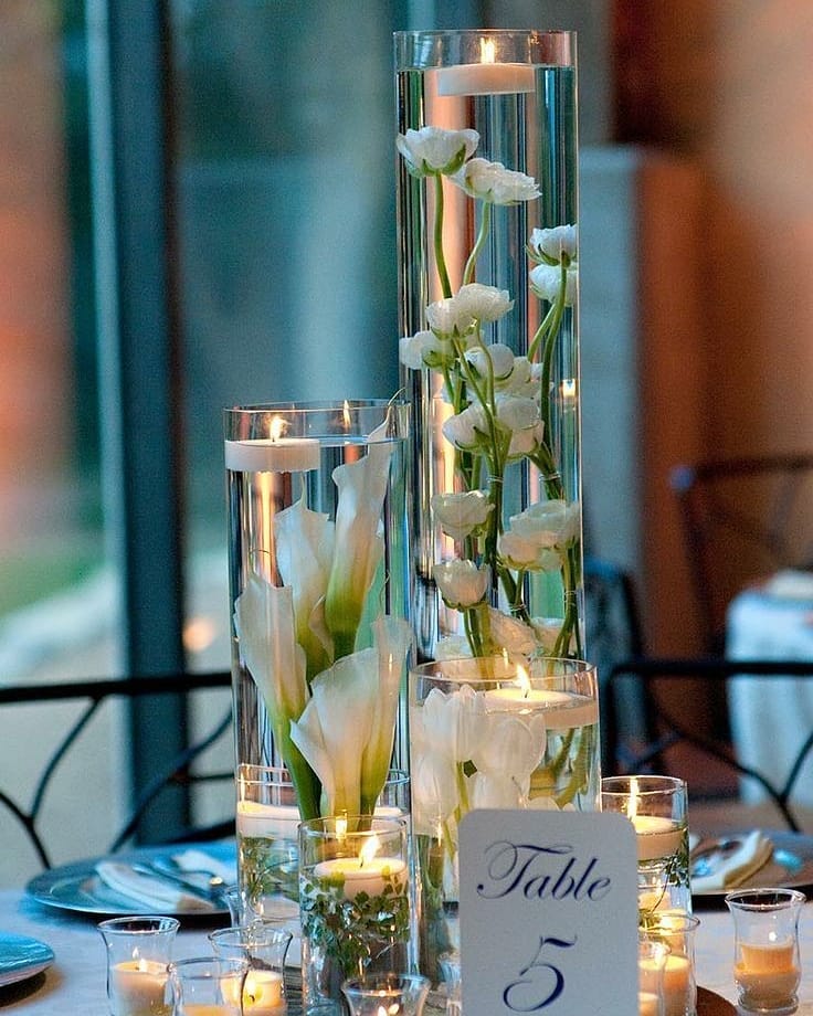 Elegant floating candle wedding centerpieces with white flowers and candles.