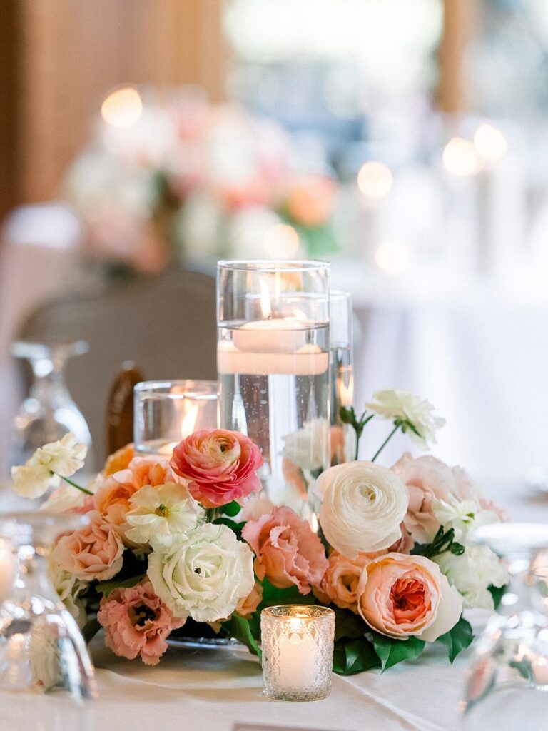 Elegant wedding centerpiece with floating candles and pastel roses for reception decor.