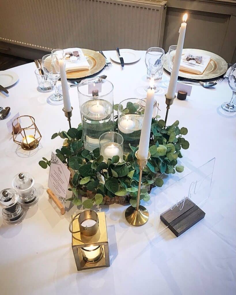 Elegant wedding centerpiece with floating candles and greenery on reception table.