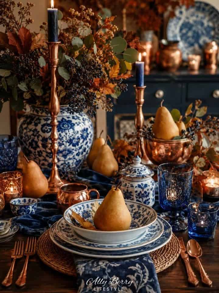 Elegant Thanksgiving table setting with blue and copper accents, pears, and floral centerpiece.