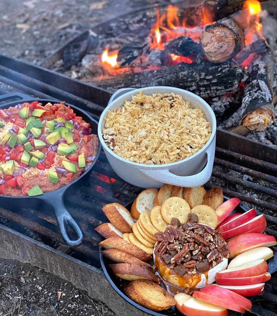 Campfire outdoor meal with pizza, rice, and snacks for a cozy bonfire night.