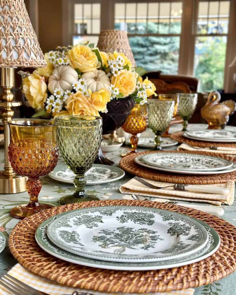 Vintage Thanksgiving tablescape with floral centerpiece, antique plates, and colorful glassware.