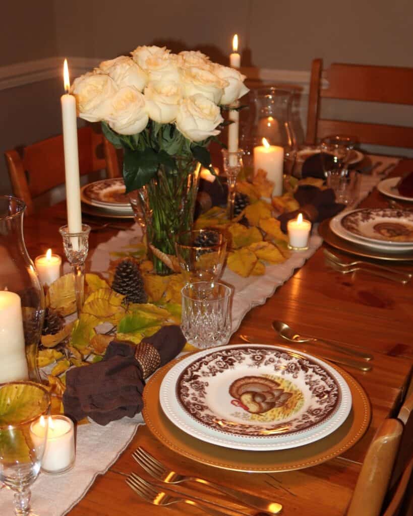 Elegant Thanksgiving tablescape with white roses candles and vintage dinnerware.