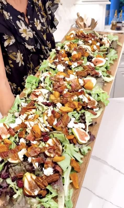 Colorful fall salad with roasted vegetables, figs, and cheese on a wooden platter.