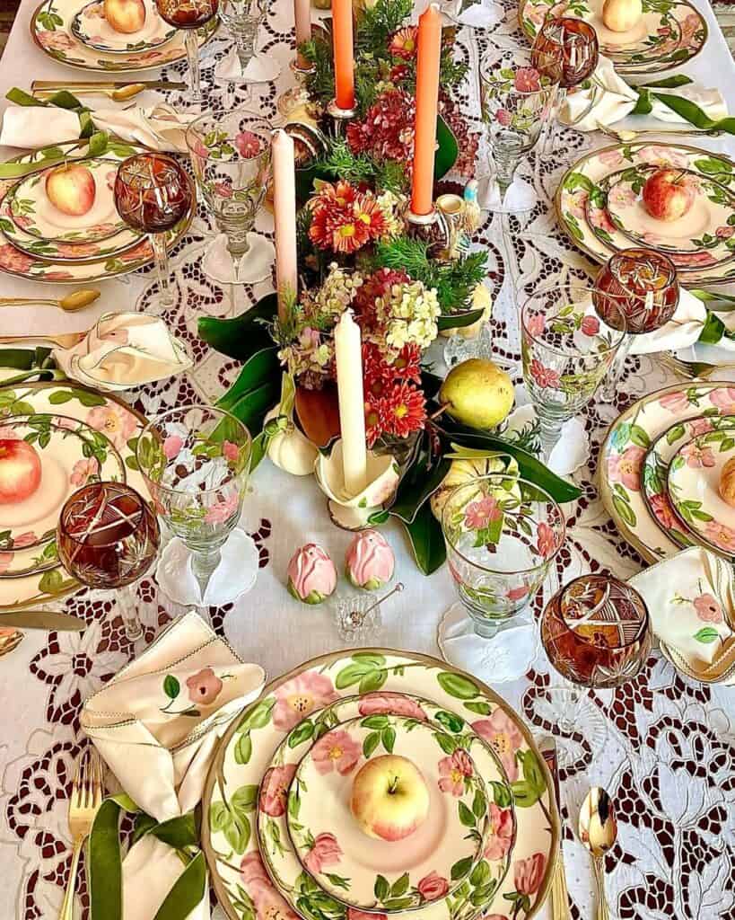Vintage Thanksgiving tablescape with floral centerpiece, apples, candles, and elegant tableware.