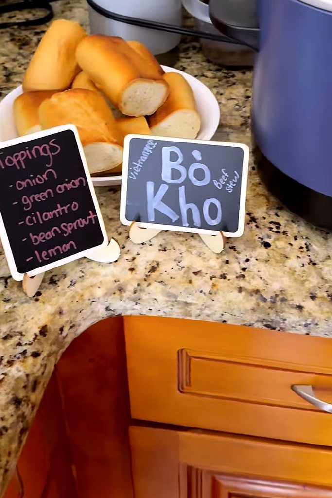 Fresh bread rolls and a Bò Kho Vietnamese soup sign on a kitchen counter.