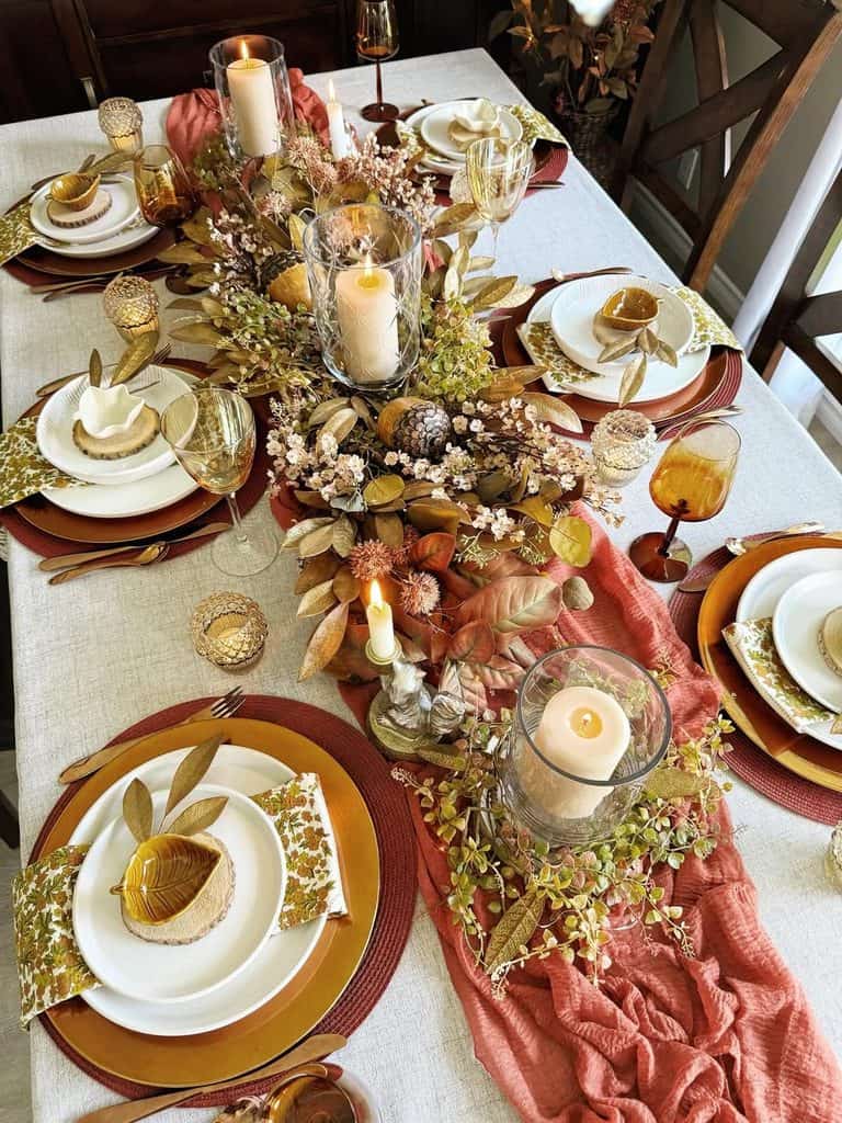 Elegant fall-themed dining table with candles, flowers, and gold accents for autumn gathering.