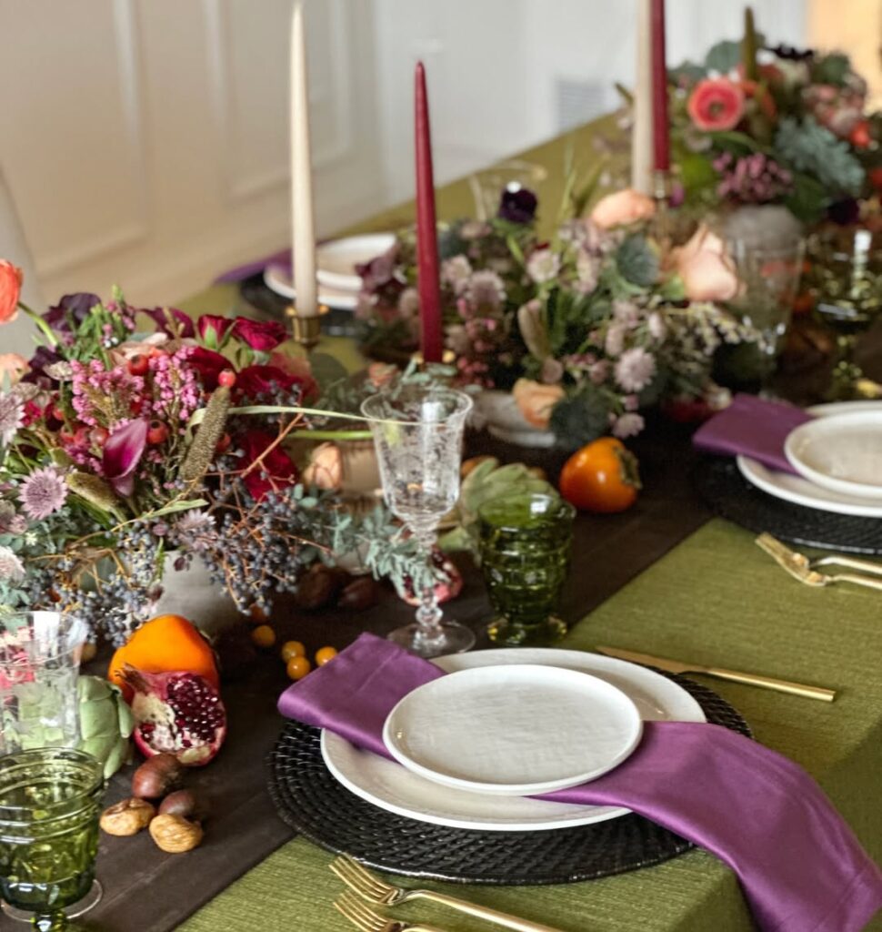 Elegant Thanksgiving table setting with floral arrangements, candles, and seasonal decor.