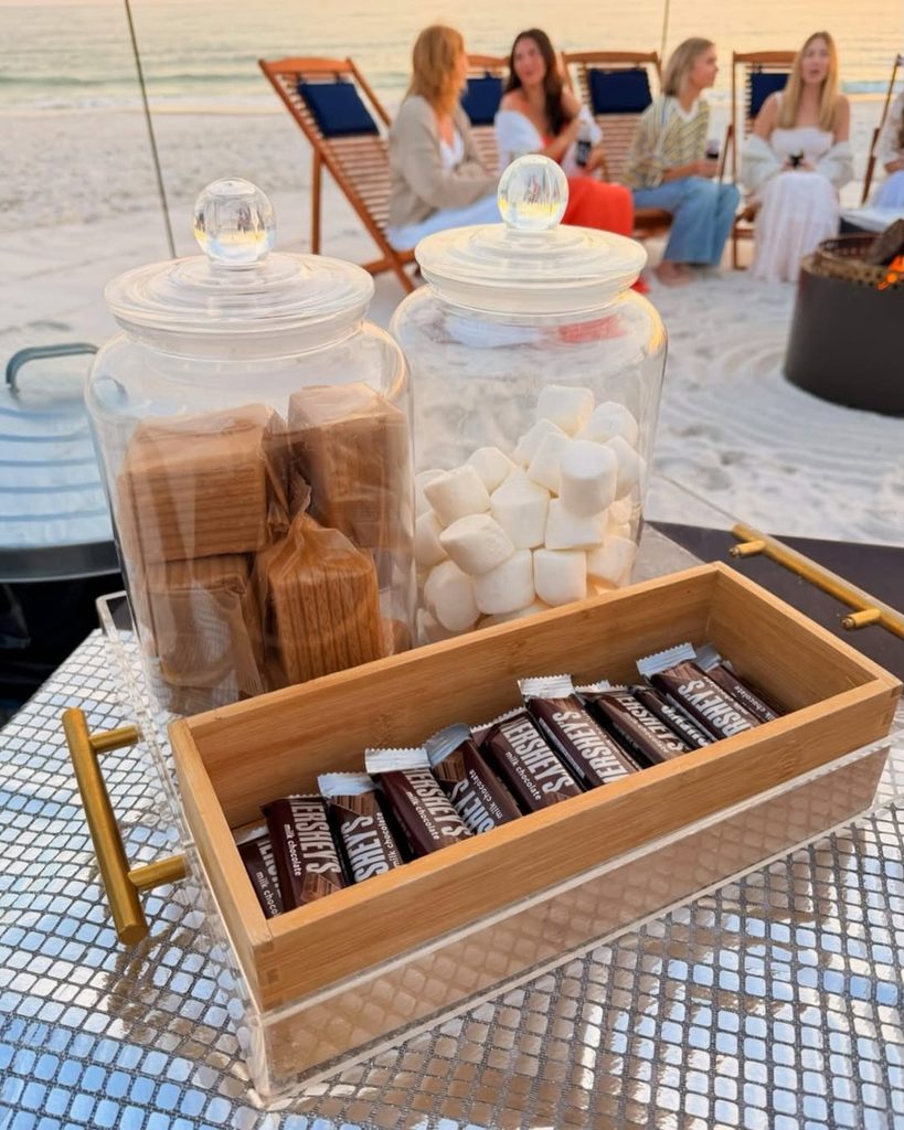 Beach bonfire setup with marshmallows, chocolate, and graham crackers for s'mores.