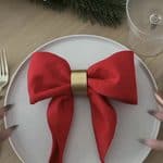 Festive holiday table setting with red napkin bow and gold napkin ring.