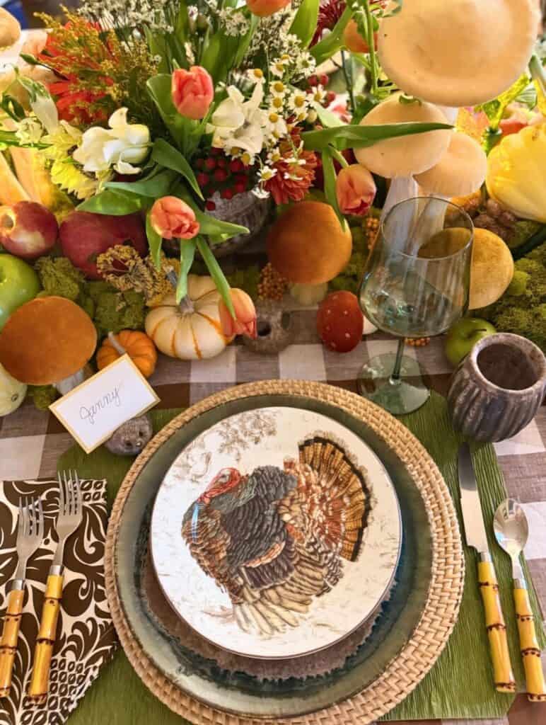 Vintage Thanksgiving tablescape with autumnal flowers, pumpkins, and turkey-themed plate.