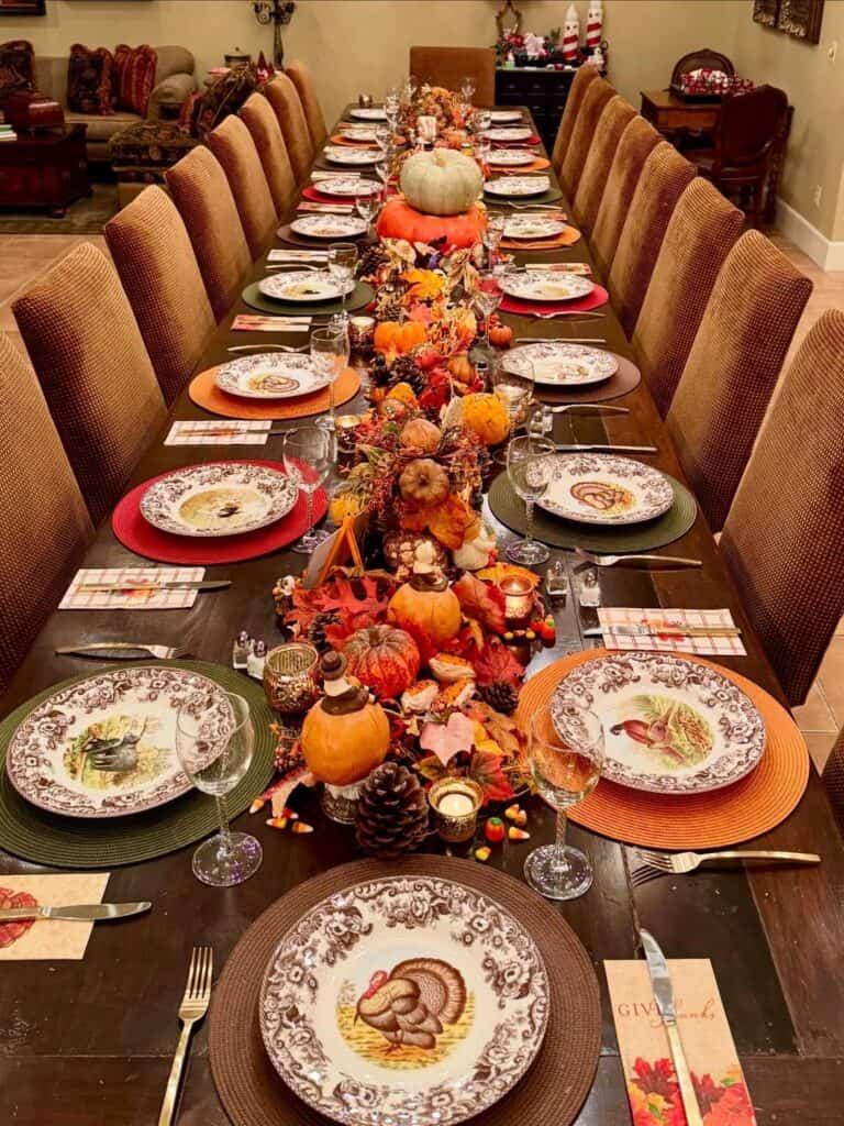 Vintage Thanksgiving tablescape with pumpkins, fall leaves, and autumn-themed dinnerware.