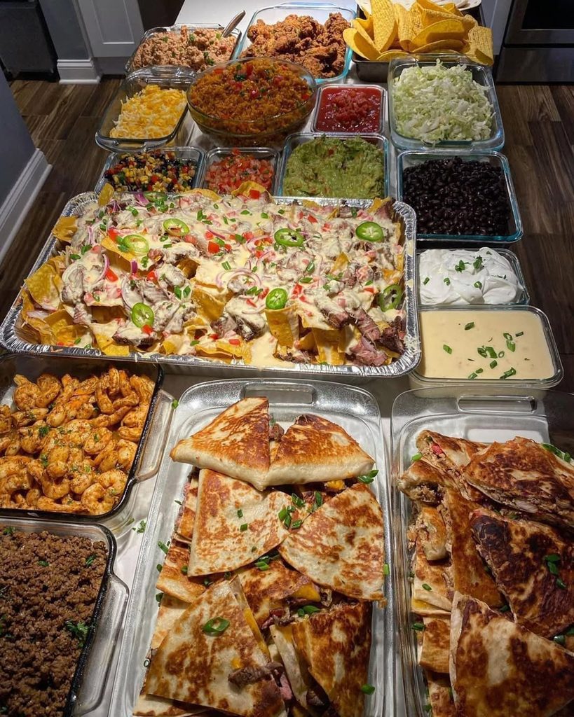 Friendsgiving feast with tacos, quesadillas, and various side dishes and toppings.