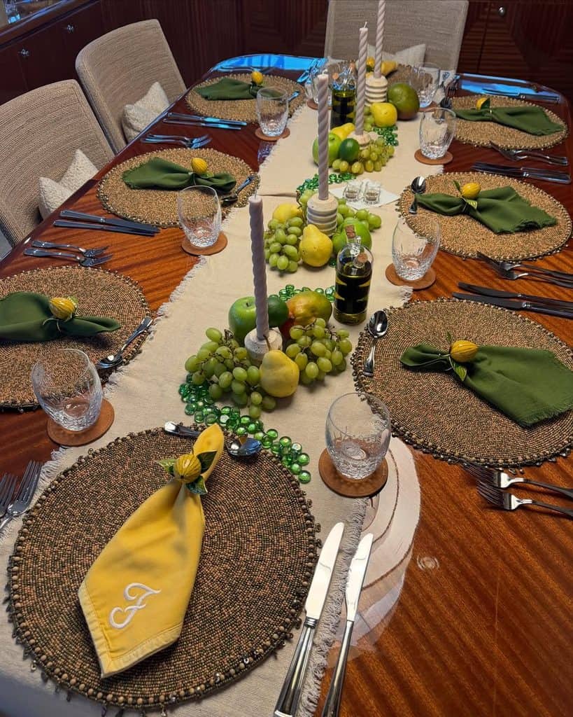 Elegant fall-themed dining table with green grapes, yellow lemons, candles, and green napkins.