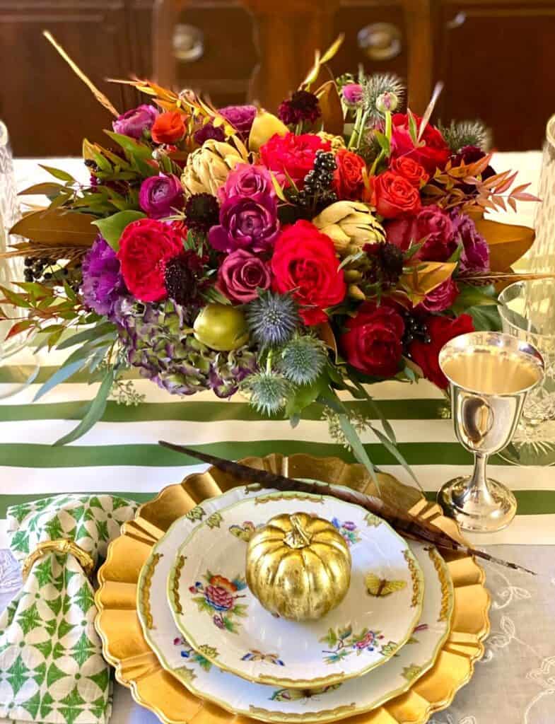 Elegant Thanksgiving table centerpiece with vibrant flowers and gold accents.
