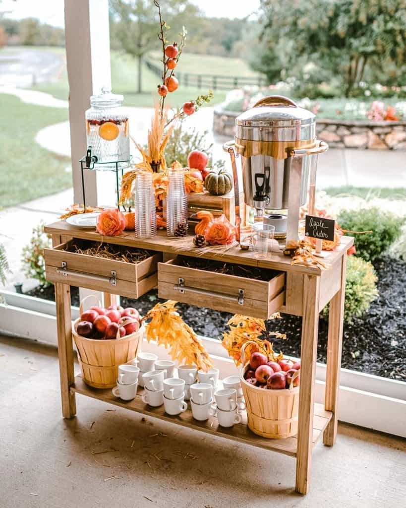 Autumn-themed beverage and snack station with apples, pumpkins, and fall decor.