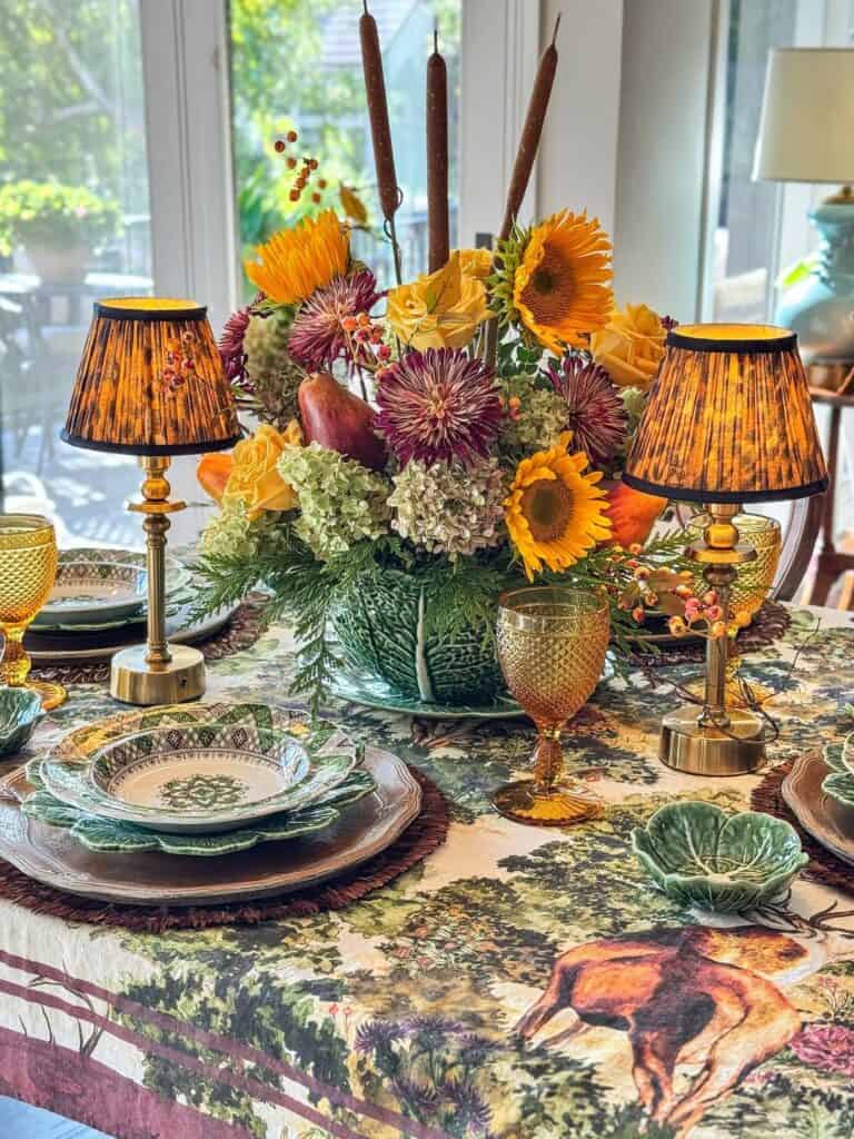 Vintage Thanksgiving tablescape with sunflower centerpiece, candles, and antique tableware.