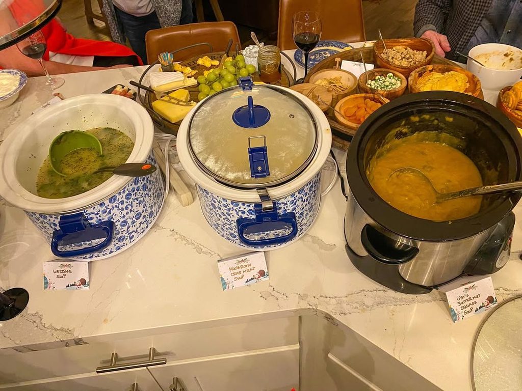 Variety of soups and toppings served at a cozy party buffet table.