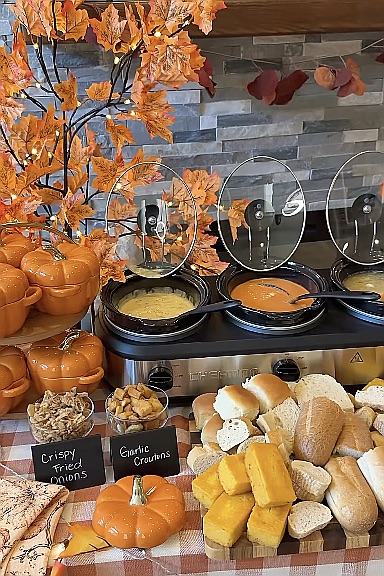 Cozy soup bar with pumpkin-shaped containers, bread, and autumn decor for a party.