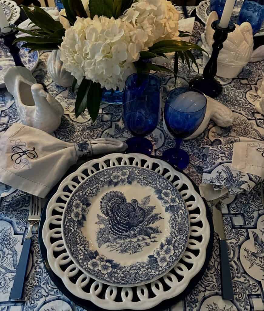 Vintage Thanksgiving tablescape with blue and white china, floral centerpiece, and elegant tableware.