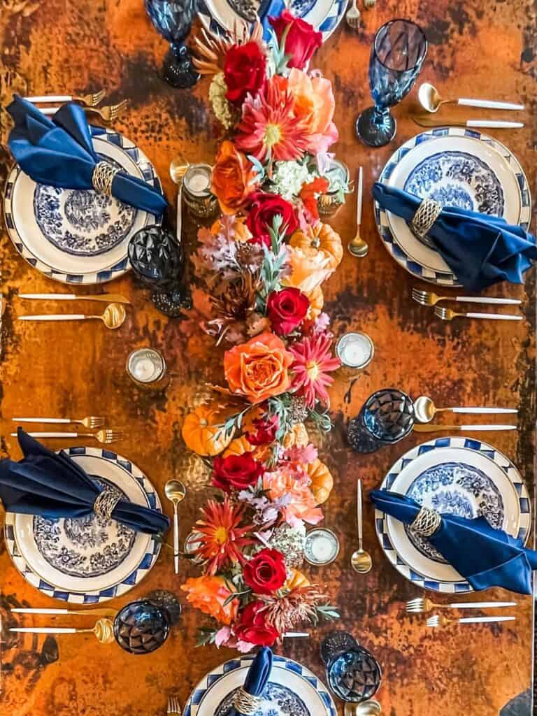 Elegant Thanksgiving table setting with blue and white dishes, floral centerpiece, and gold accents.