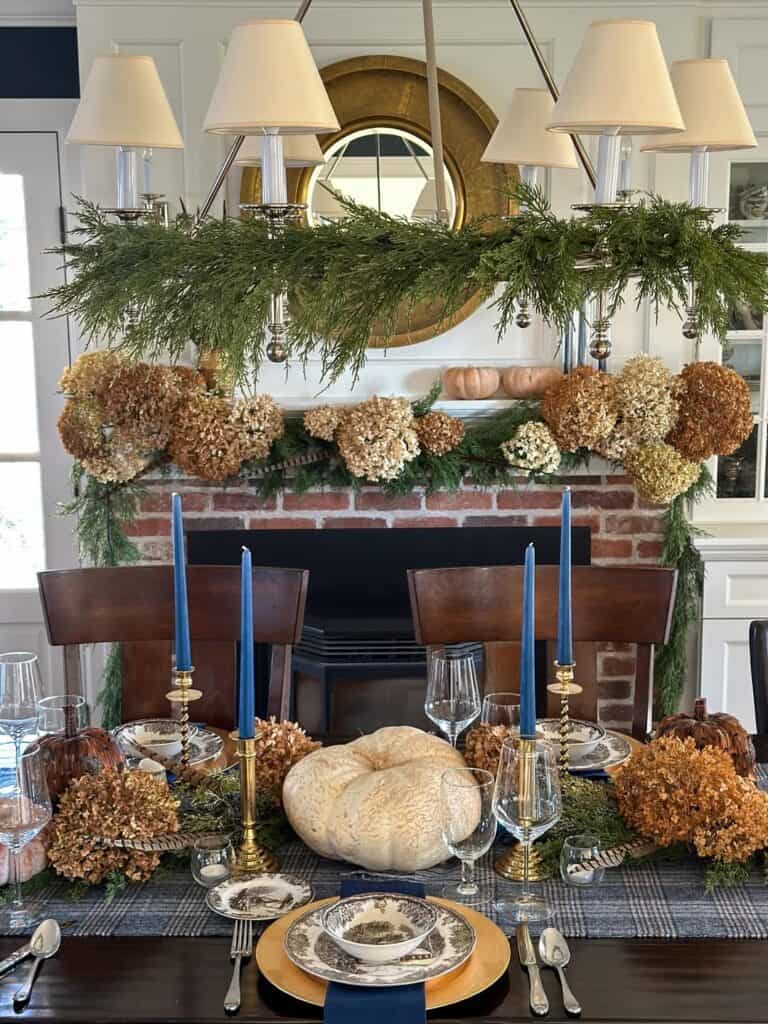 Vintage Thanksgiving tablescape with hydrangeas, candles, and pumpkin centerpiece in a cozy dining室.