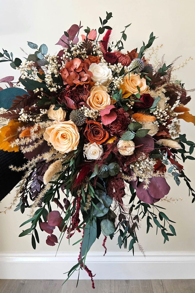 Elegant autumn wedding bouquet with roses, eucalyptus, and dried foliage.