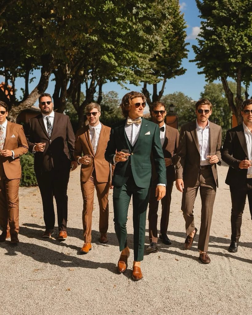 Stylish men in suits walking outdoors on a sunny day for fall wedding event.