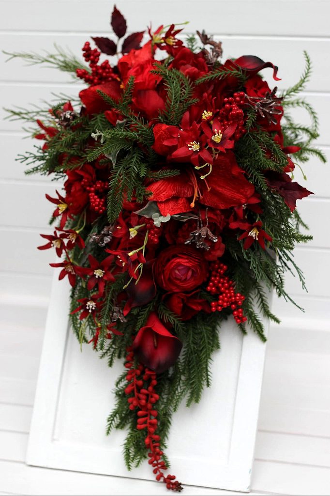 Elegant red winter wedding bouquet with roses, berries, and greenery for romantic occasions.
