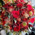 Elegant romantic winter wedding bouquet with red roses and greenery.