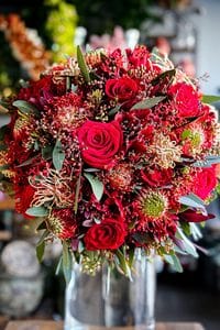 Elegant romantic winter wedding bouquet with red roses and greenery.