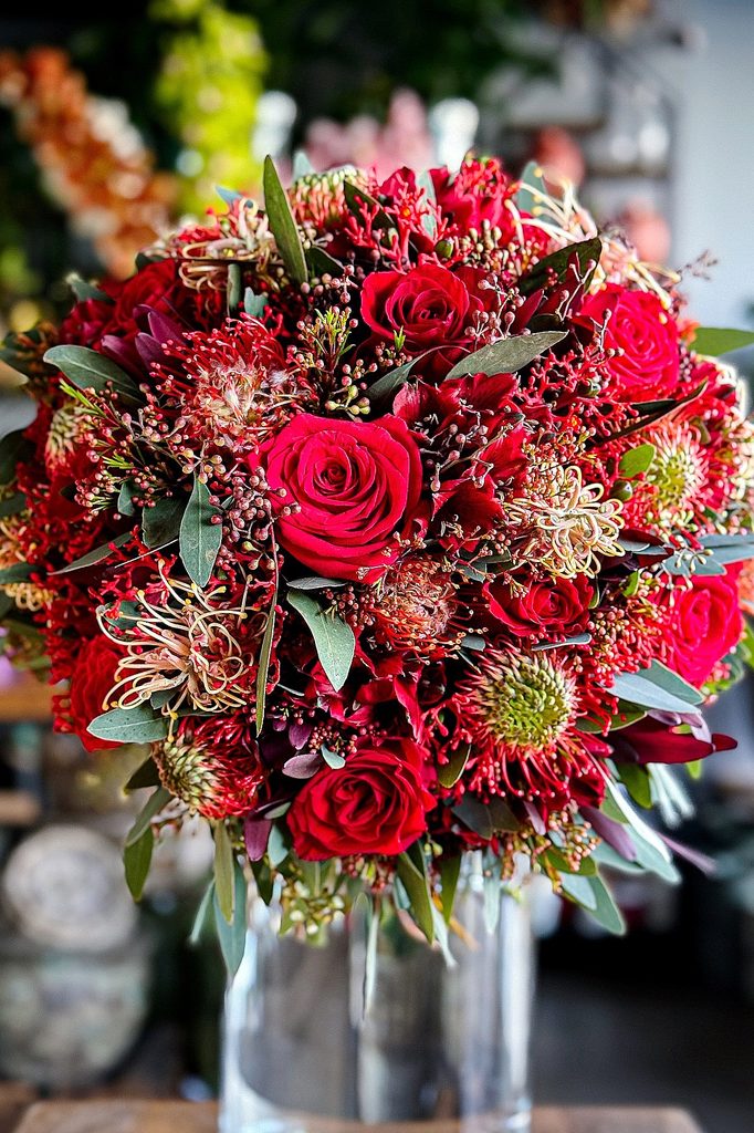 Elegant romantic winter wedding bouquet with red roses and greenery.