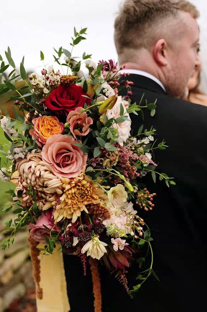 Romantic winter wedding bouquet with roses, dahlias, and greenery for wedding decor.