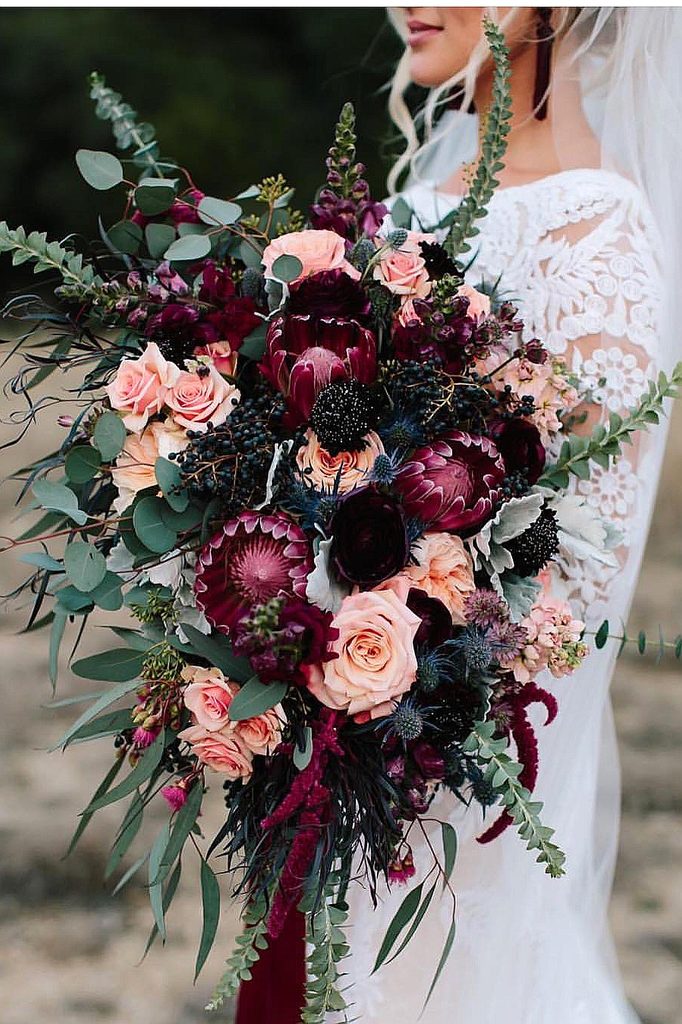 Elegant wedding bouquet with pink roses, dark purple flowers, and greenery for winter wedding.