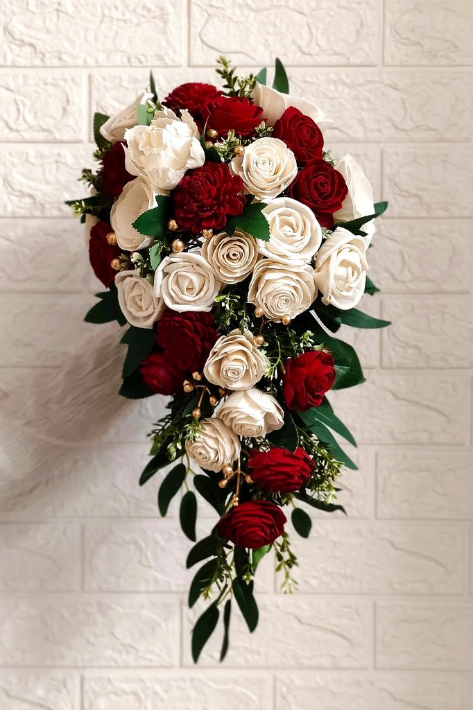 Elegant winter wedding bouquet with red and white roses and greenery.