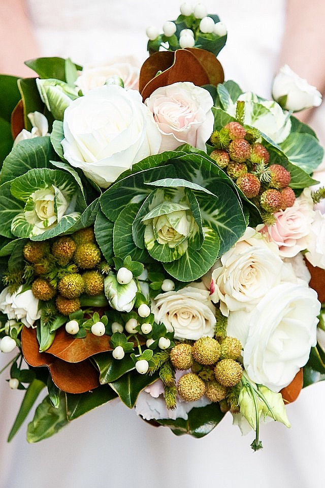 Elegant winter wedding bouquet with white roses, greenery, and brown accents.