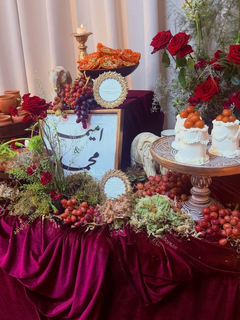 Elegant fall wedding dessert table with roses, grapes, and seasonal treats.