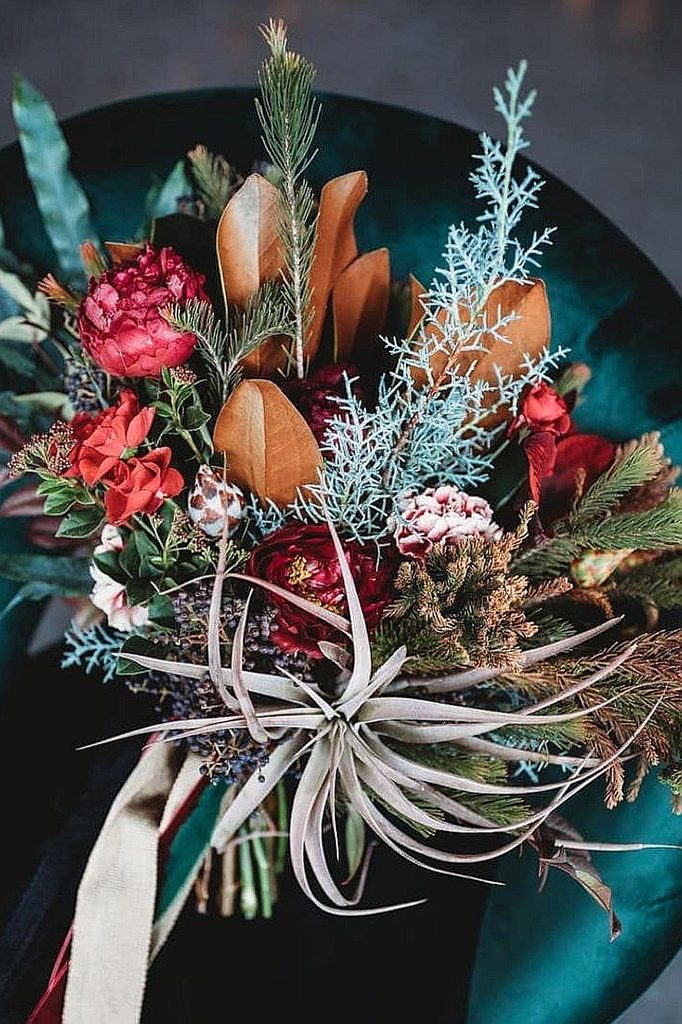 Elegant winter wedding bouquet with red, pink, blue, and brown floral accents.