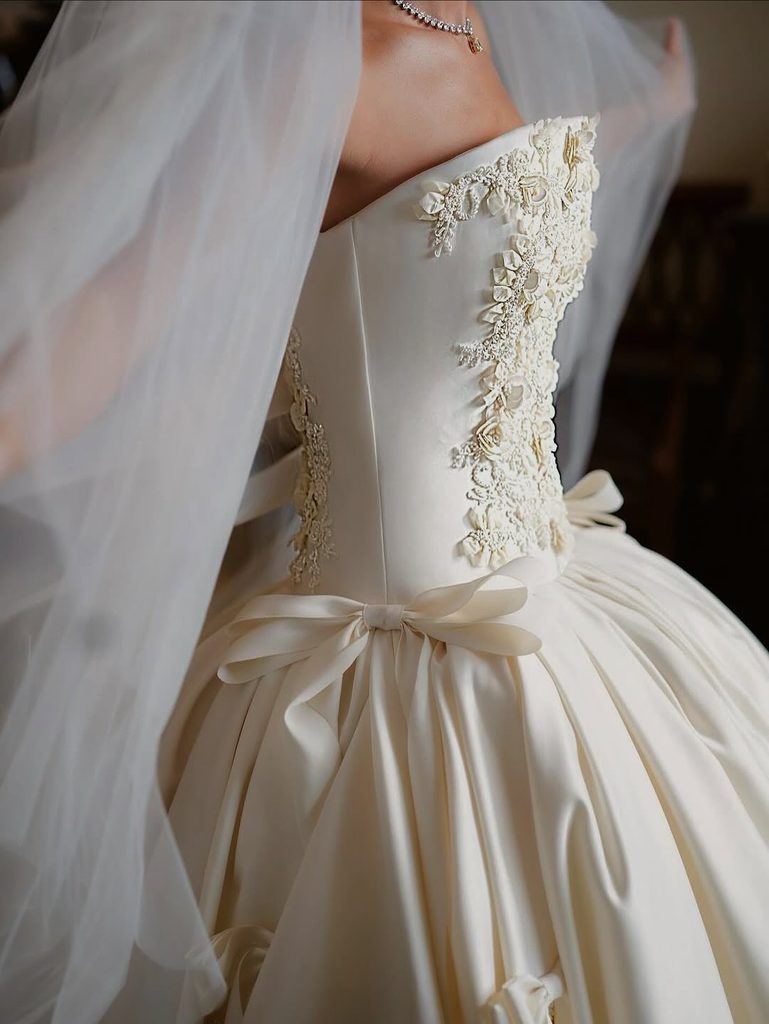 Elegant ivory wedding dress with floral embroidery and satin bow for fall wedding.